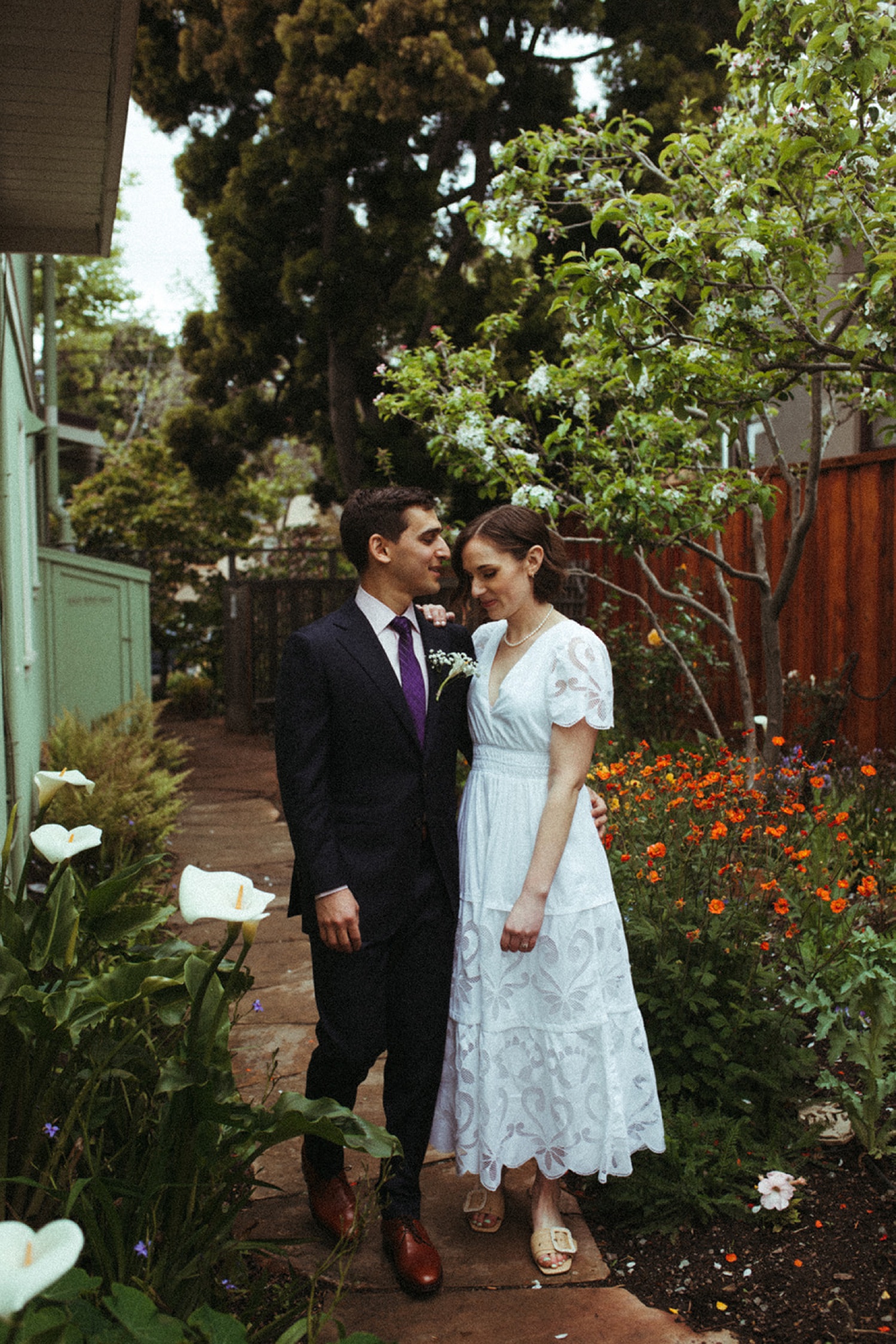 Couple walk in a backyard garden on their wedding day in Oakland.