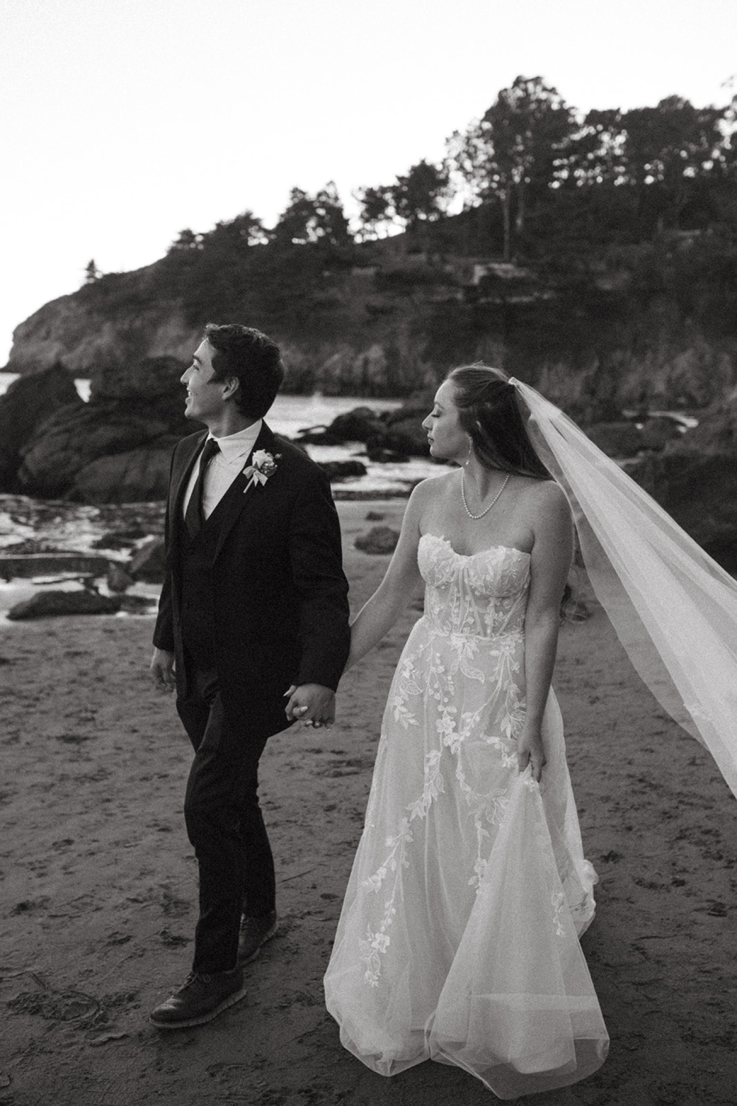 Bride and groom walk on beach on their wedding day