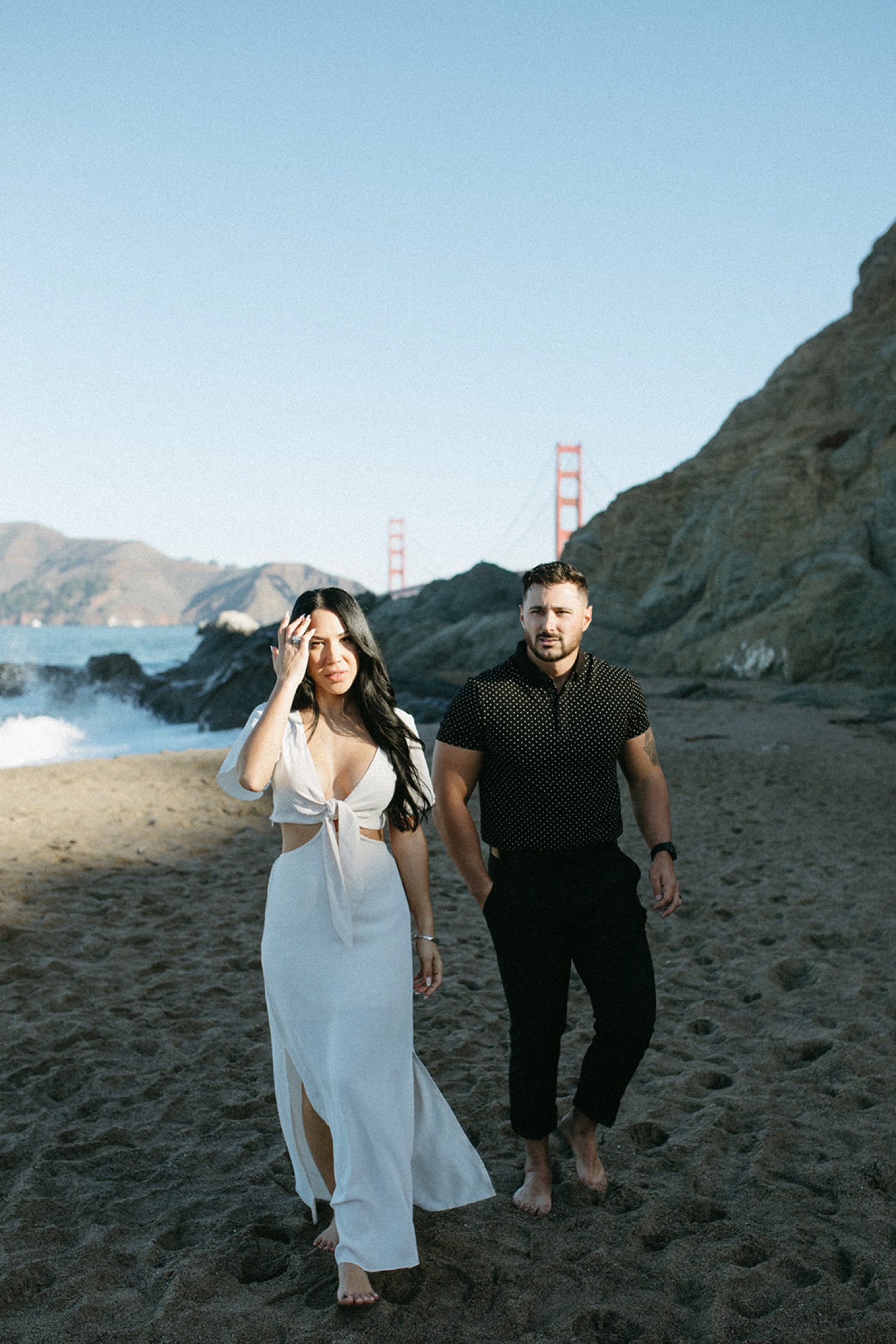Couple walk on beach in San Francisco during their engagement photos