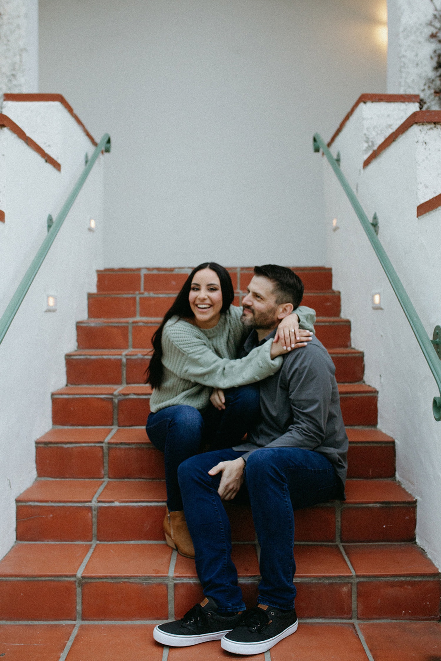 Couple hugs on stairs during their engagement photos.
