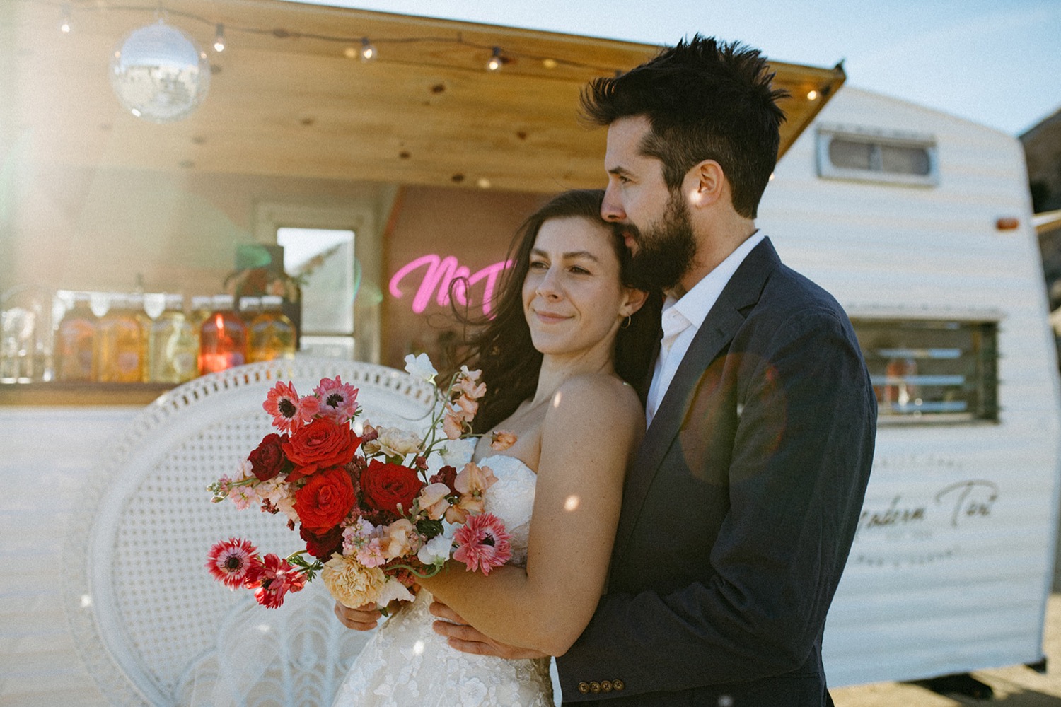 Bride and groom pose with drink trailer in California.