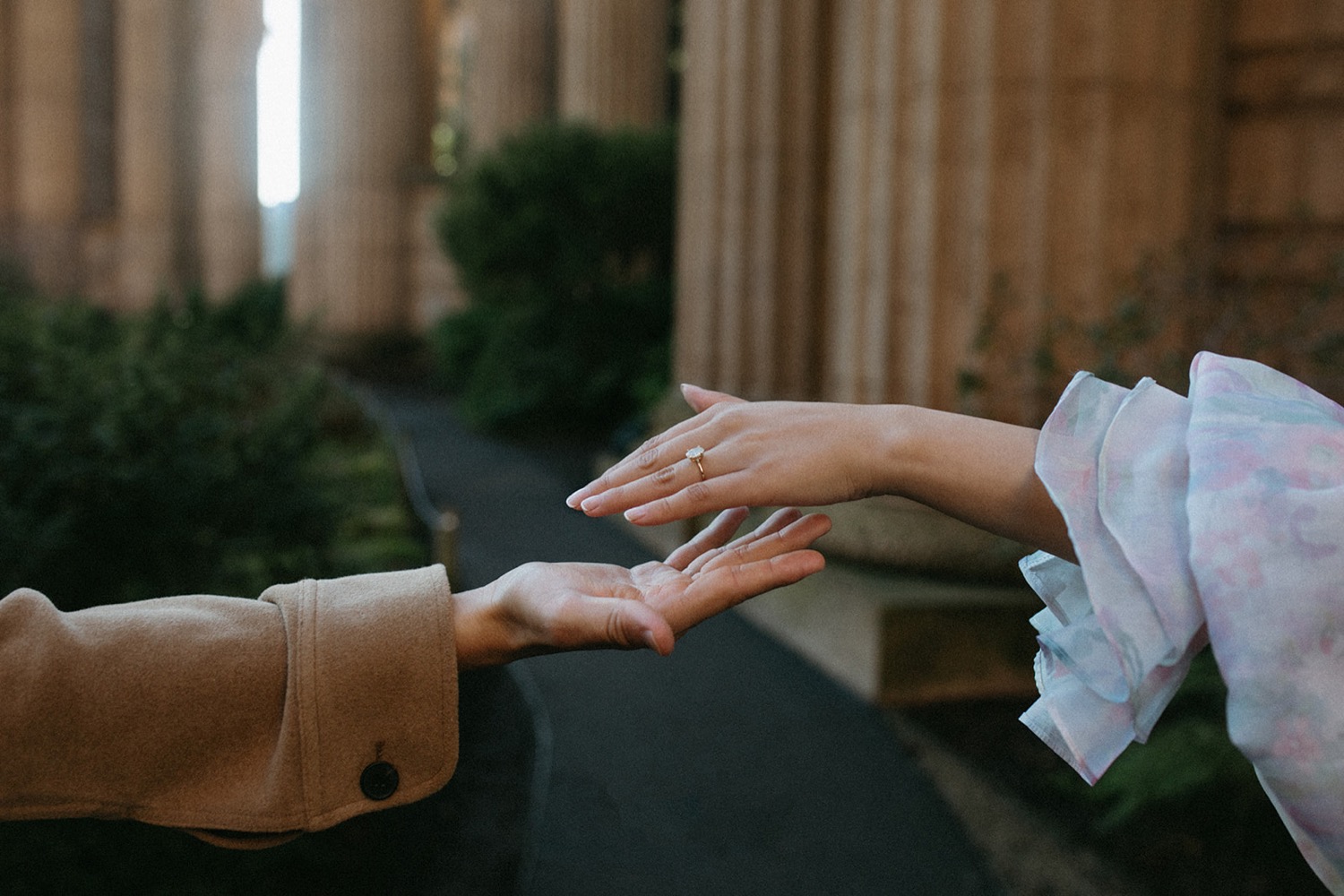 Couple reaches out their hands to each other in San Francisco during their engagement photos