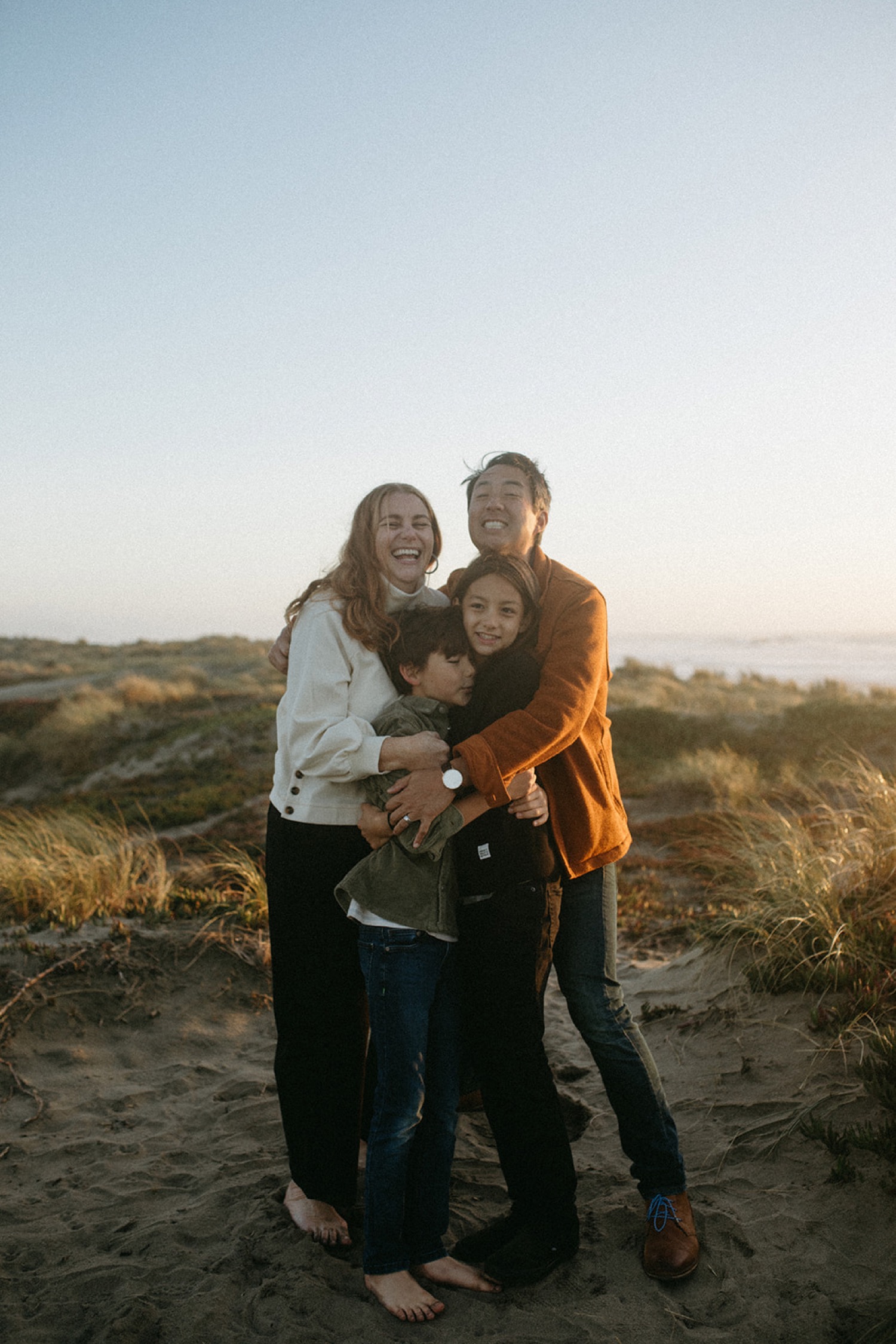 Family hugs on a sand dune in San Francisco during a photoshoot.