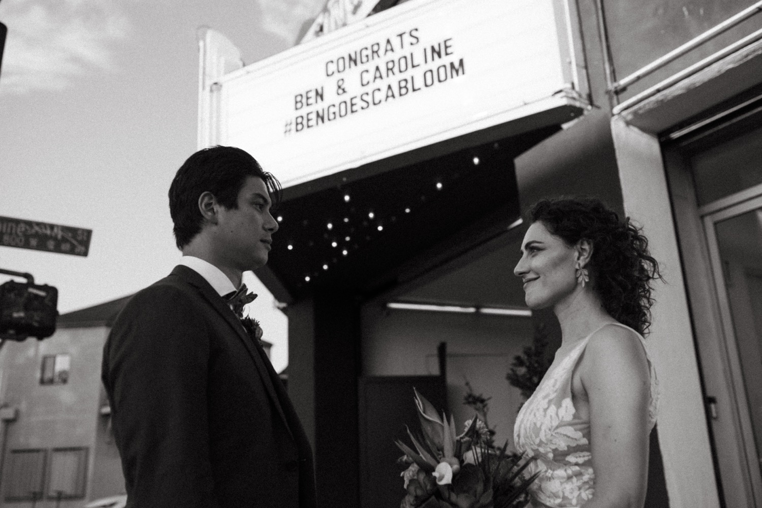 Bride and groom gaze at each other under theatre marquee on their wedding day in Los Angeles.