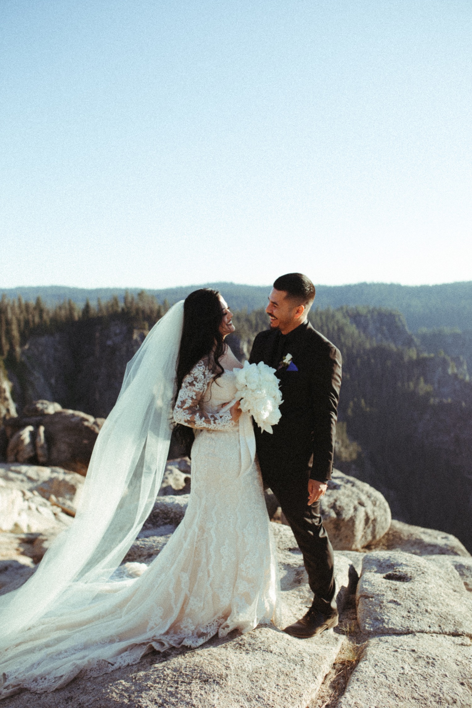 Bride and groom pose with beautiful view on their wedding day at Yosemite National Park.