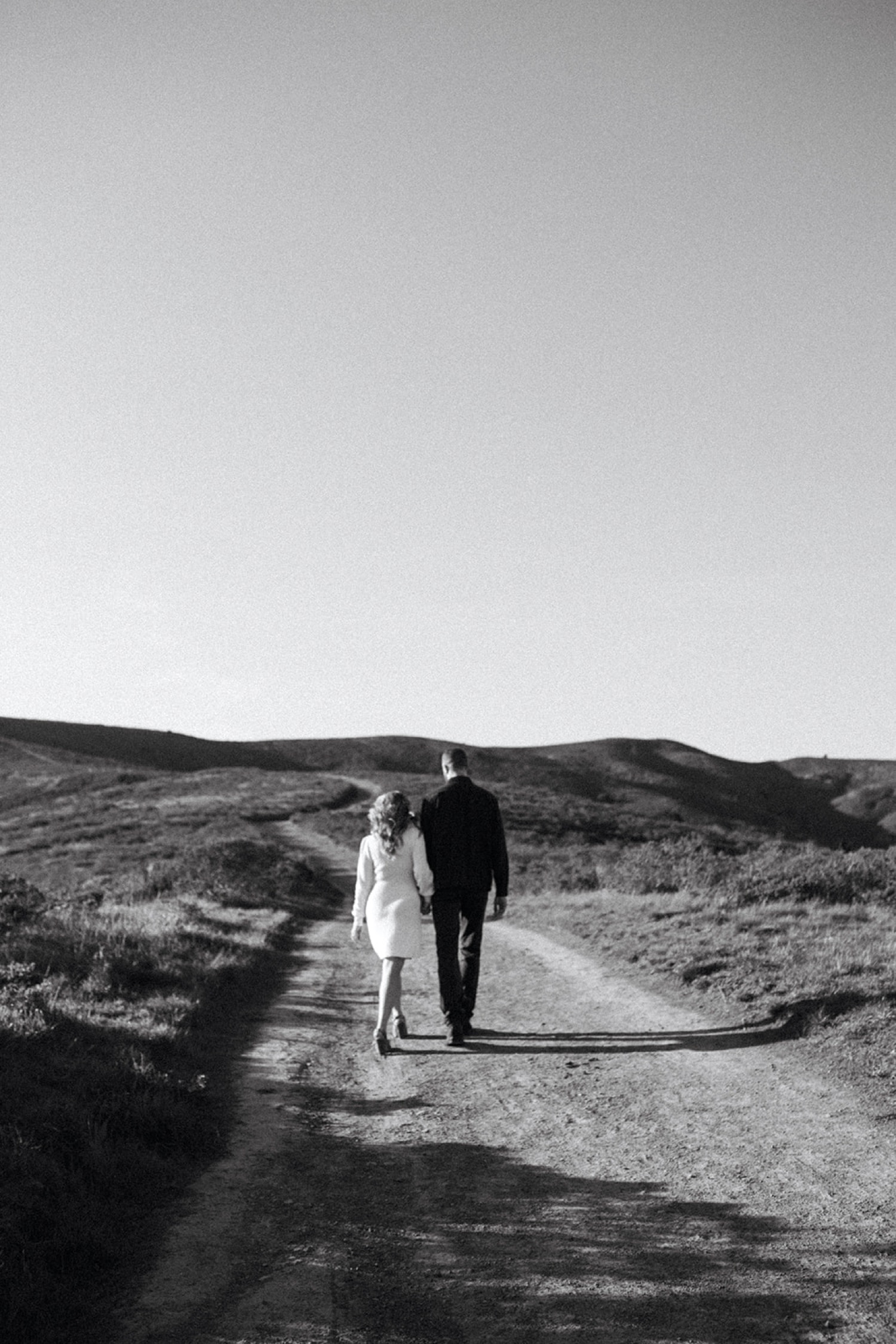 Couple walk on dirt path during their engagement session in the Bay Area.